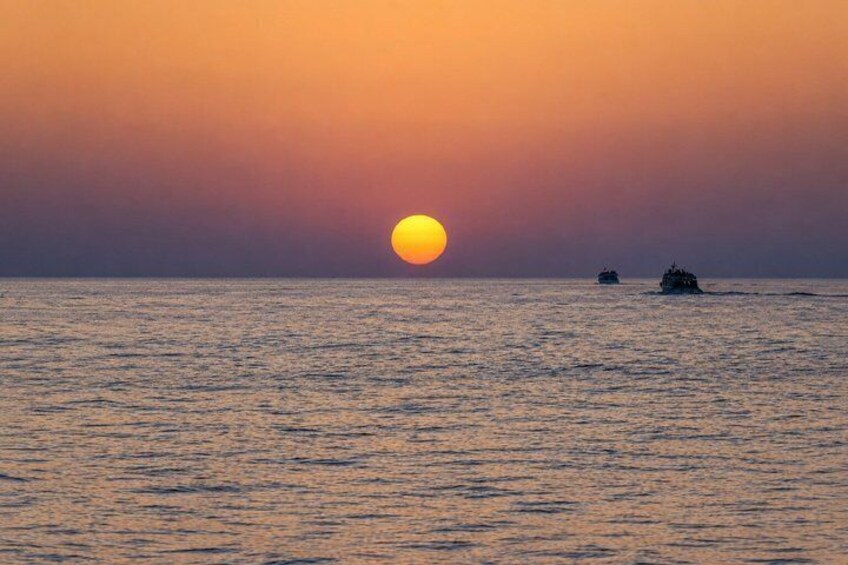 A sunset over the ocean with two boats. 2