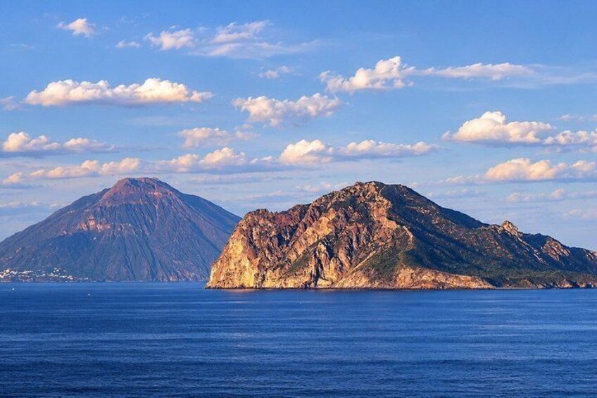 A coastal landscape with a prominent mountain and a smaller hill in the foreground. 3