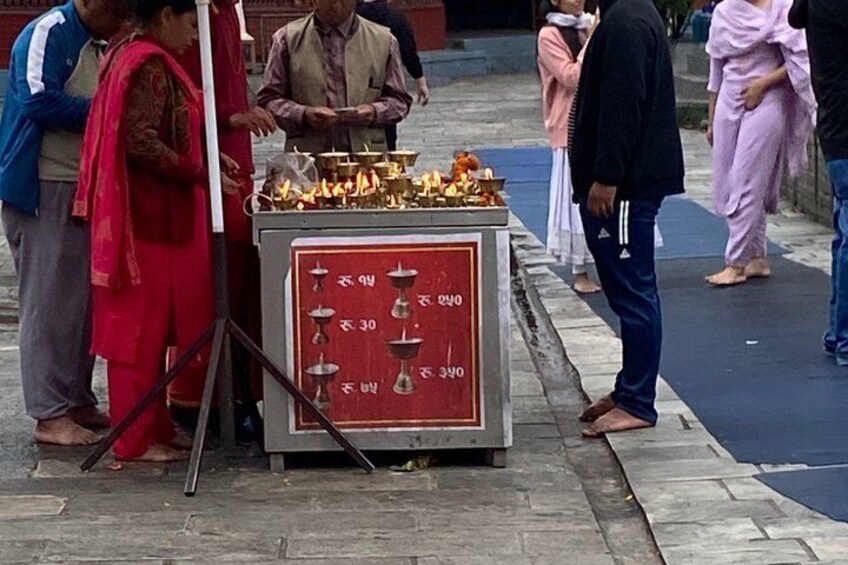 A street vendor with a red cash box and lit oil lamps. 4