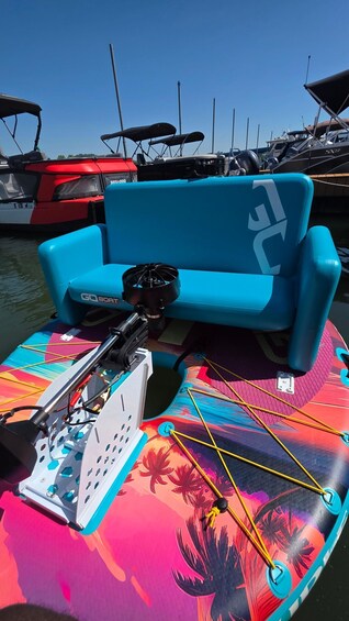A colorful inflatable boat with a blue sofa and a fan, docked at a marina with other boats. 5