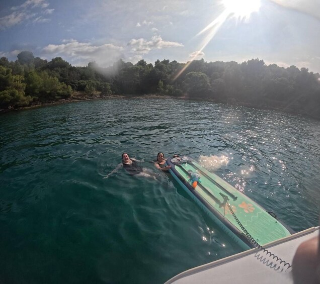 Two people floating on a body of water with a boat in the foreground. 4