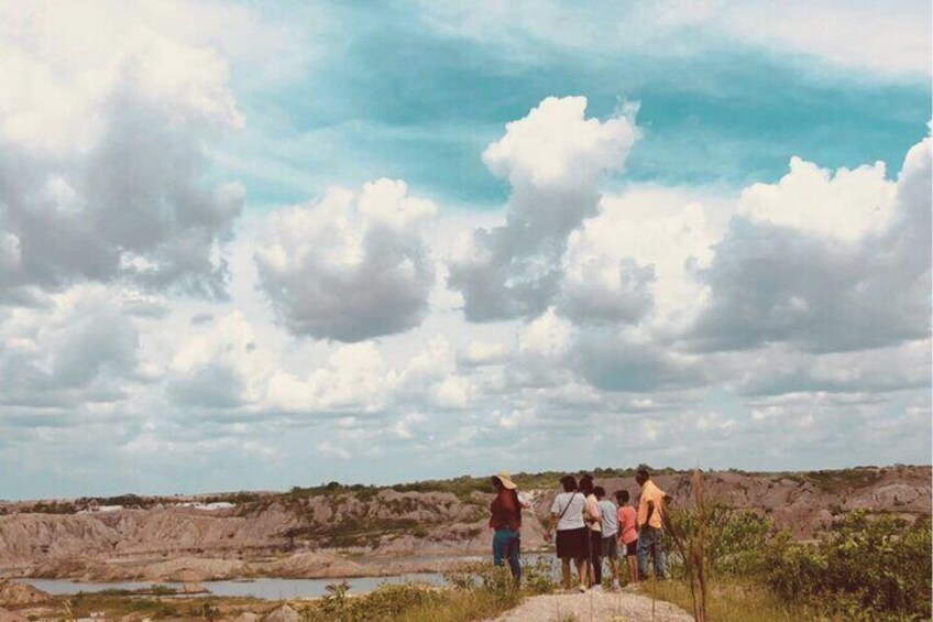 A group of people standing on a rocky outcrop overlooking a dry riverbed. 5