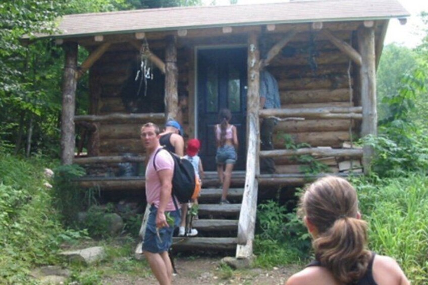 A rustic log cabin with a porch, surrounded by greenery. 4