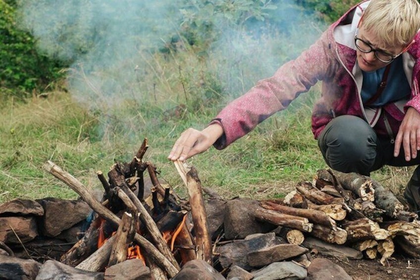 A person tending a campfire in a natural setting. 3