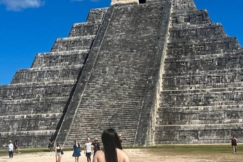 A large pyramid structure with tourists around it. 3