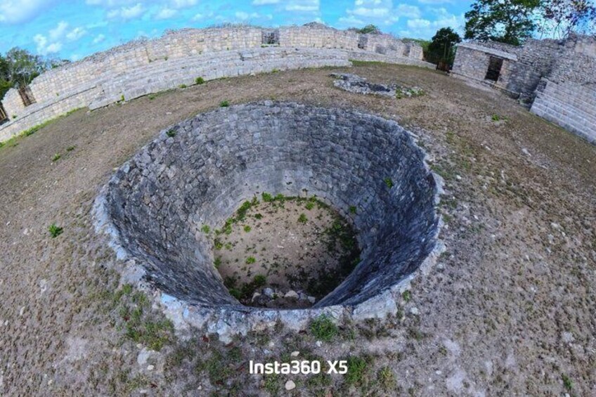 A circular stone structure with a central depression, surrounded by a stone wall. 5