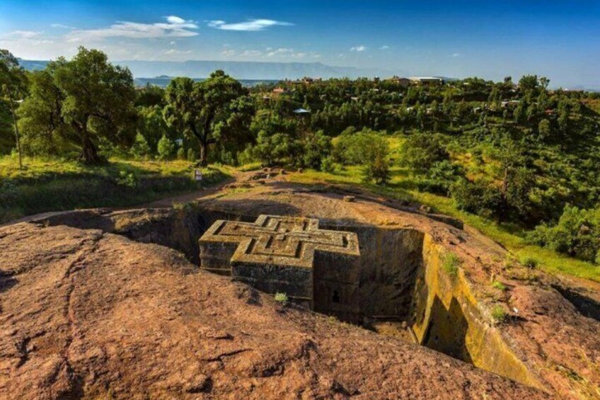 An ancient stone structure with a maze-like design surrounded by a forested landscape. 5