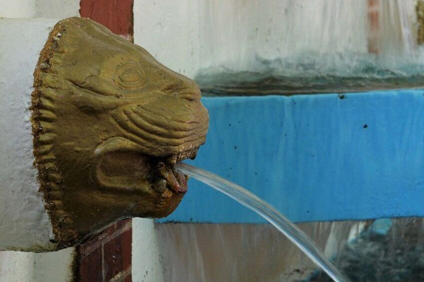 A stone lion head with water flowing from its mouth. 2