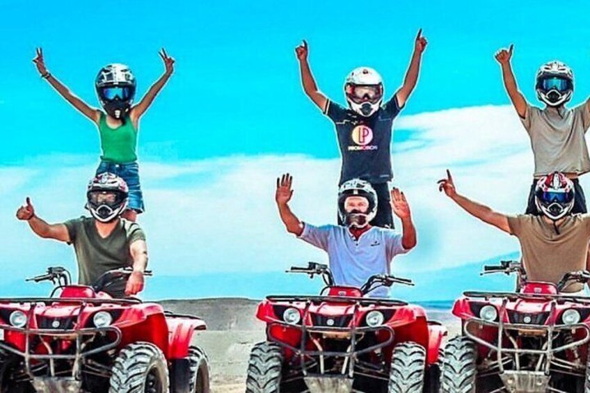 Four people on quad bikes with the ocean in the background. 2