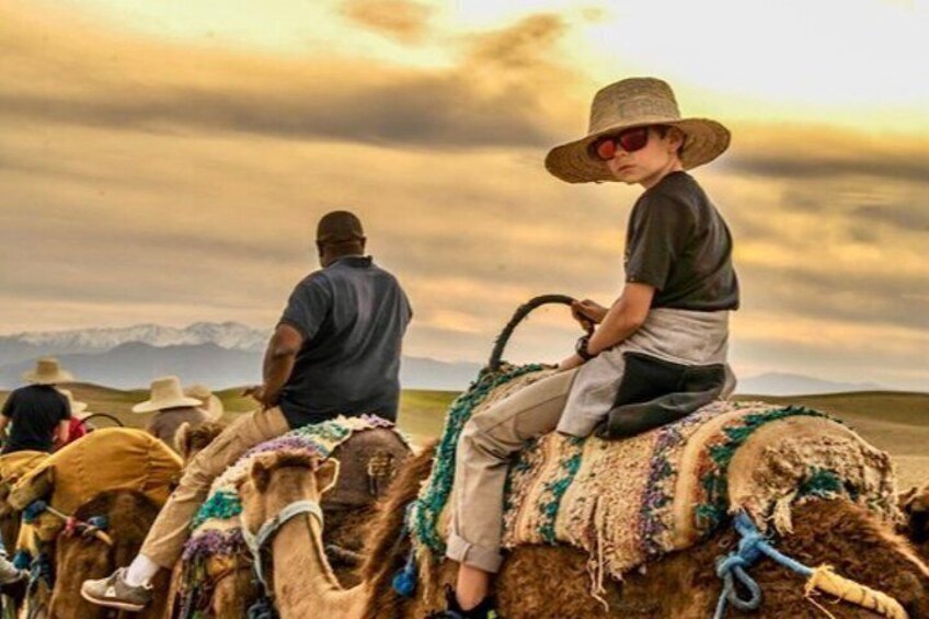 A person riding a camel in a desert landscape with mountains in the background. 2