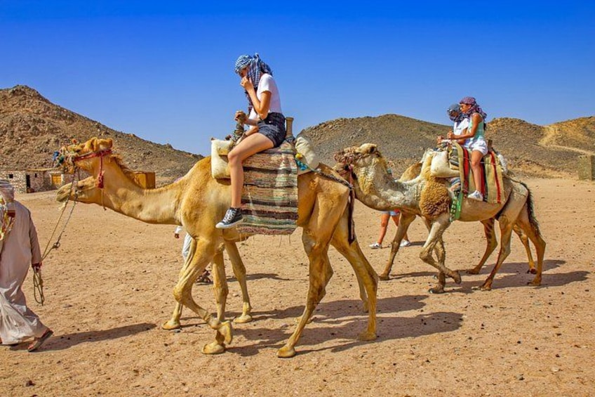 Three camels with riders in a desert landscape. 2