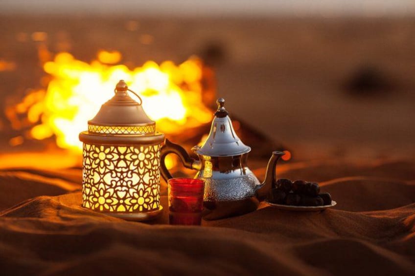 A traditional Moroccan tea set with a lantern, a teapot, a cup, and a plate of dates on a bedspread. 4