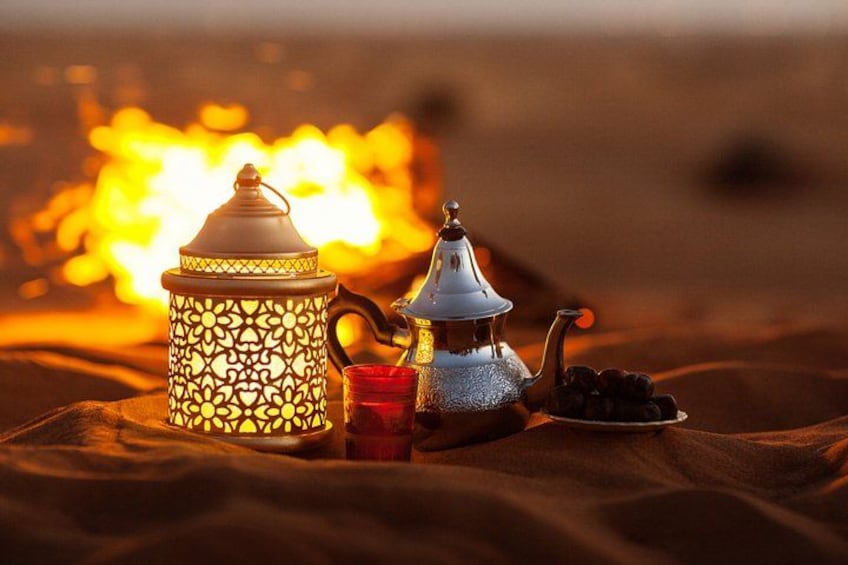 A traditional Moroccan tea set with a lantern, a teapot, a cup, and a plate of dates on a blanket. 5