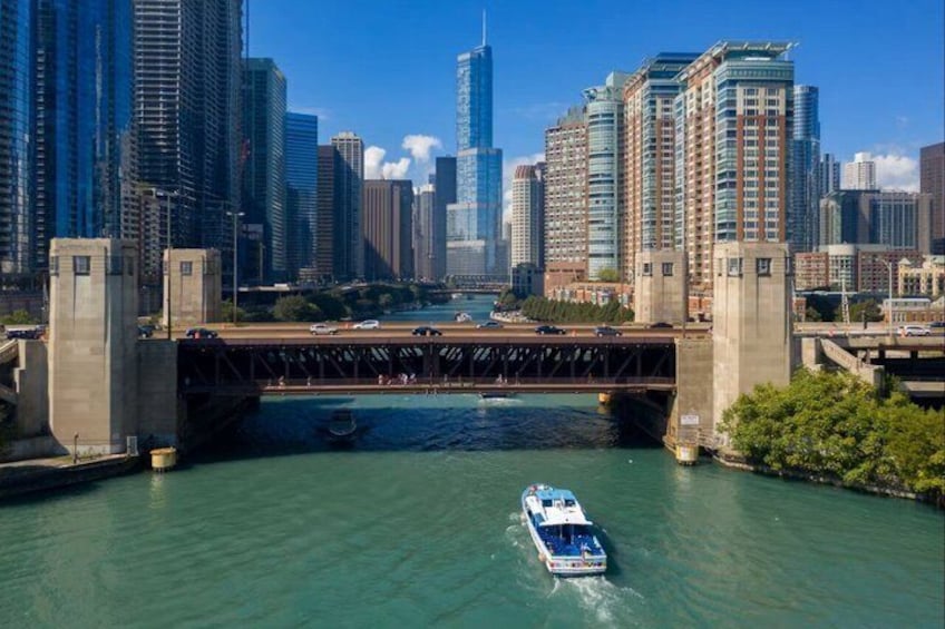 A river with a bridge, a boat, and a city skyline with tall buildings. 3