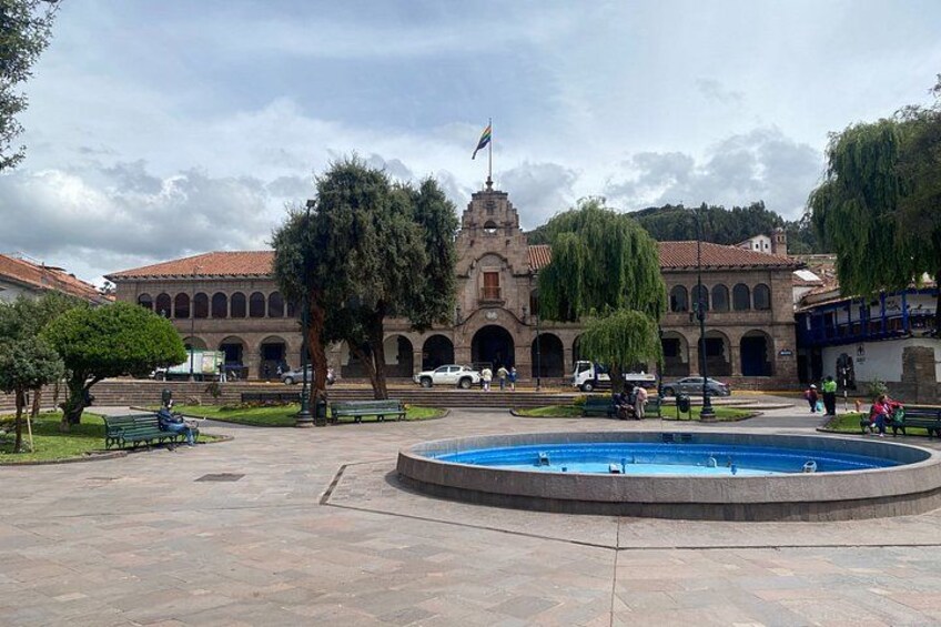 A courtyard with a fountain, a building with arches, and a flag. 3