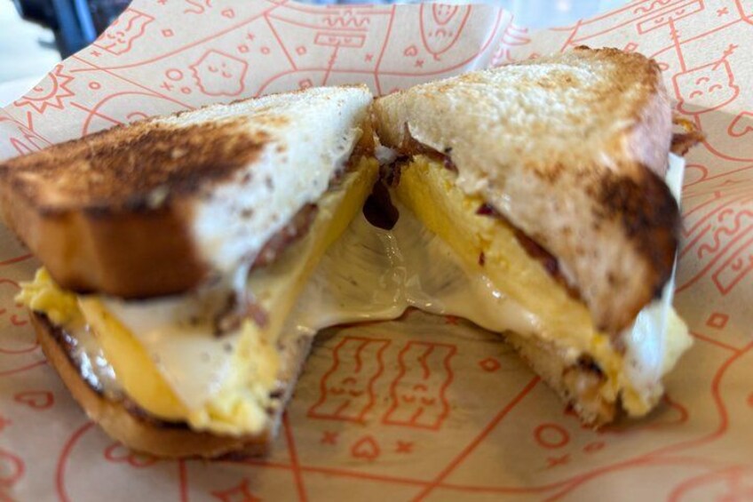 A grilled sandwich cut in half on a paper with doodle designs. 2