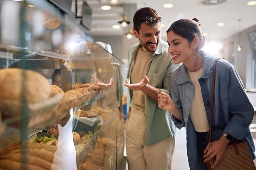 Two people looking at pastries in a bakery display case. 3