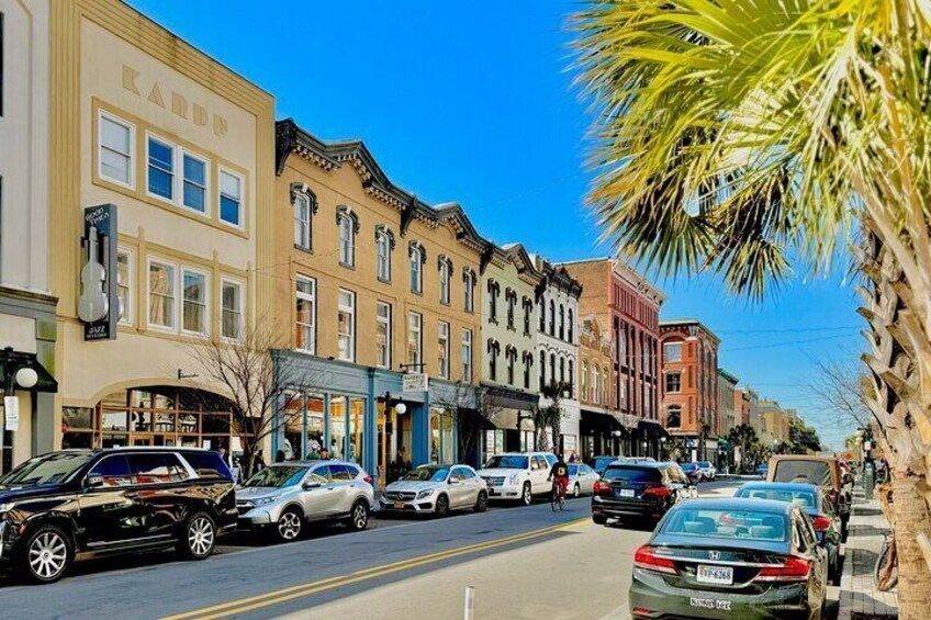 A street lined with historic buildings, parked cars, and a palm tree. 5