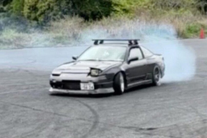 A car drifting on a paved surface with smoke. 5