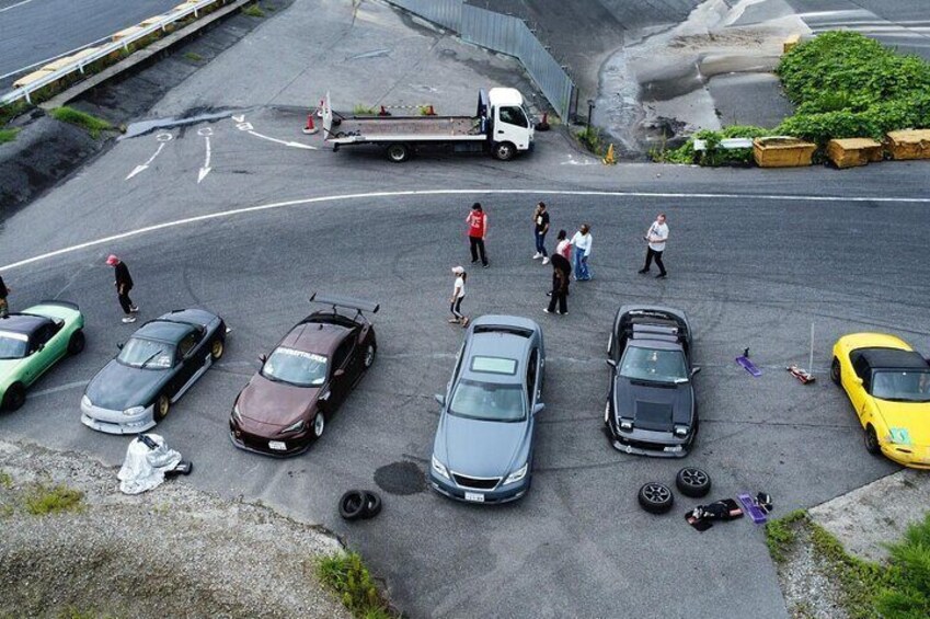 A parking lot with several cars, a truck, and people walking around. 4