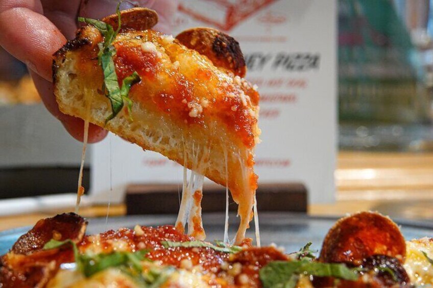 A slice of pizza with melted cheese being lifted from a pizza. 3