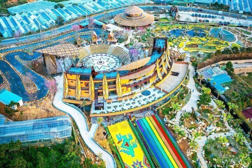 A large, colorful building with a circular central area, surrounded by a variety of structures and greenery. 1