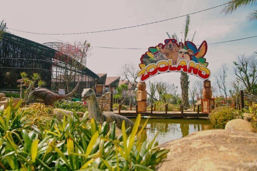 A dinosaur-themed entrance sign with a dinosaur sculpture in the foreground. 2