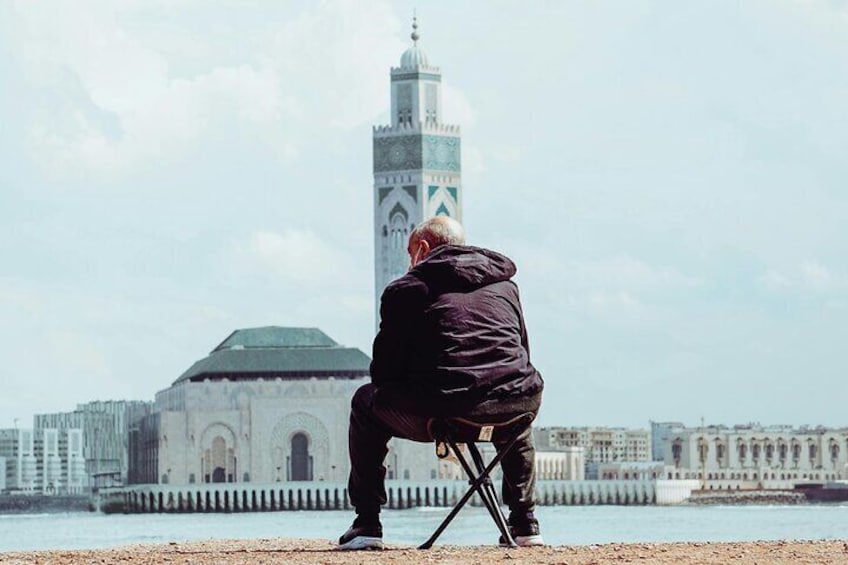 A person sitting on a tripod in front of a large building with a tower. 3
