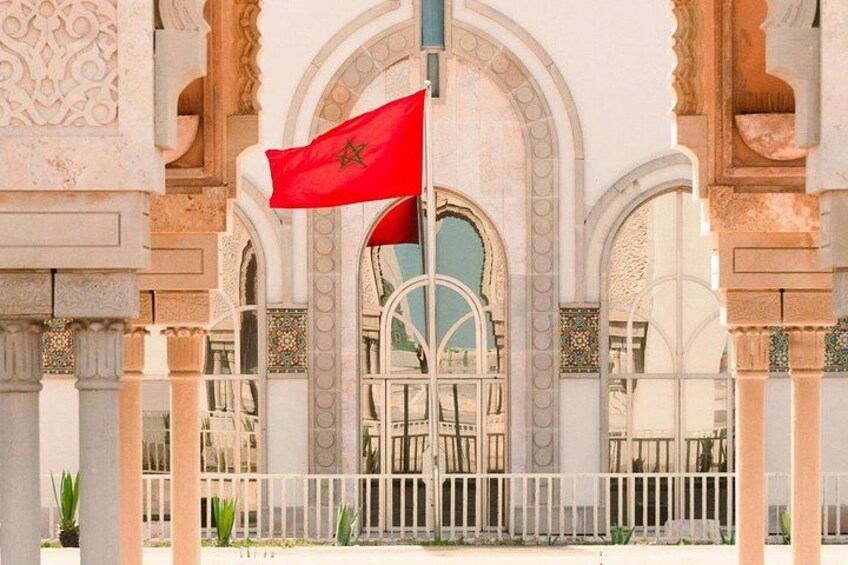 A red flag with a green emblem, white columns, and arches. 3