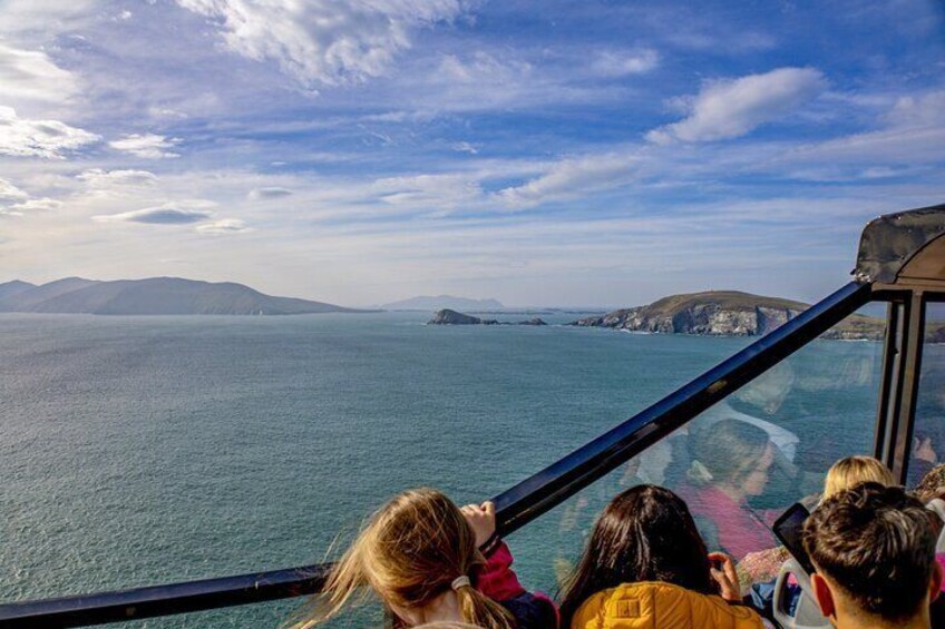 A group of people on a glass-bottomed boat tour, overlooking a calm sea with distant landforms. 4