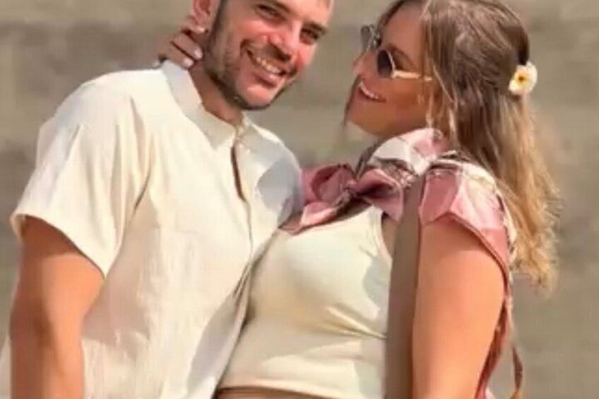 Two people embracing, one wearing a white shirt and the other a pink top with a bow. 2