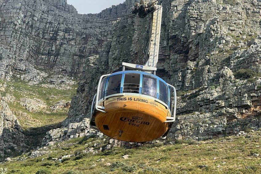 A cable car with 'THIS IS LIVING' written on it, suspended between rocky cliffs. 5