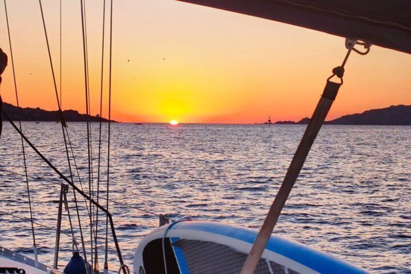 A sunset over water with a boat and a distant lighthouse. 5