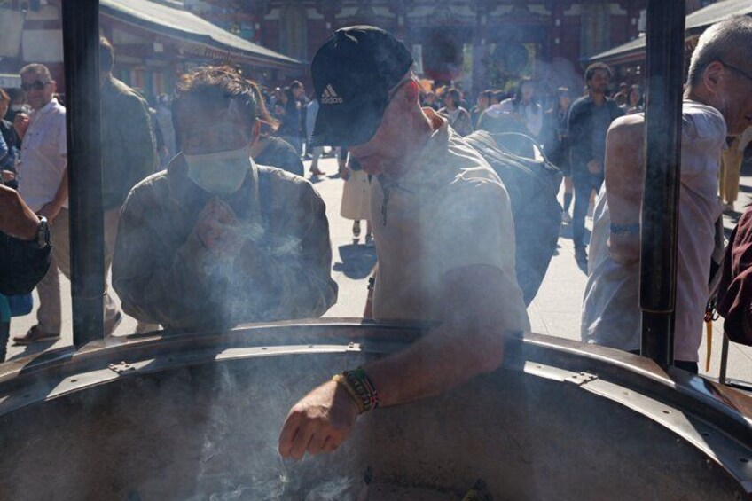 A person cooking outdoors with steam rising from a large pot. 2