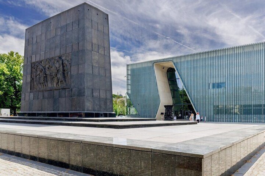 A modern building with a unique curved entrance and a large square structure with bas-relief sculptures. 3
