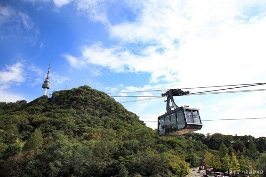 A cable car ascending a hill with a tower in the background. 4