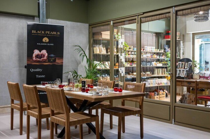 A dining area with a table set for six, surrounded by wooden chairs, with a glass display case in the background. 1
