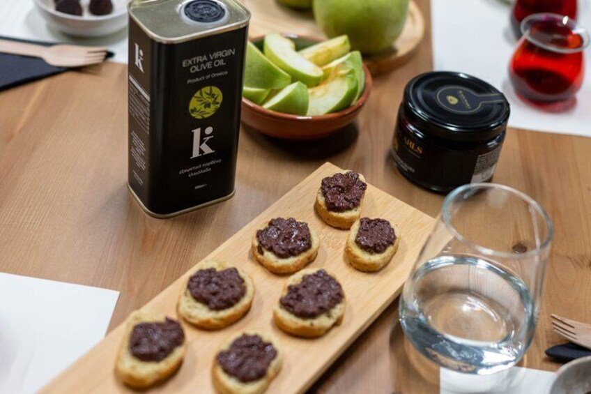 A can of extra virgin olive oil, a jar of jam, and a glass of water on a wooden table. 5