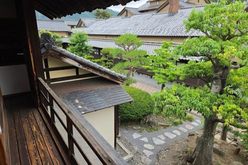 A traditional Japanese garden with a wooden deck, stone pathway, and well-maintained trees. 5