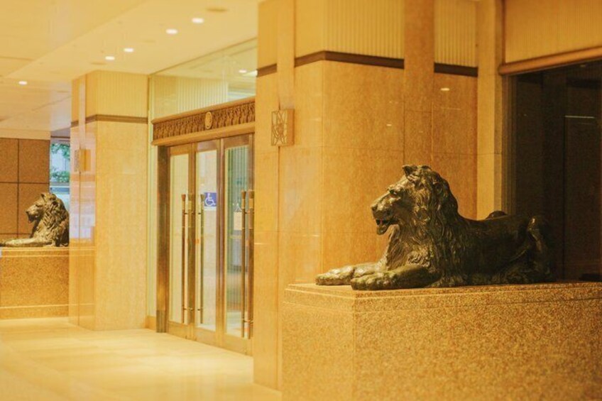 A lobby with marble flooring and two bronze lion statues. 2