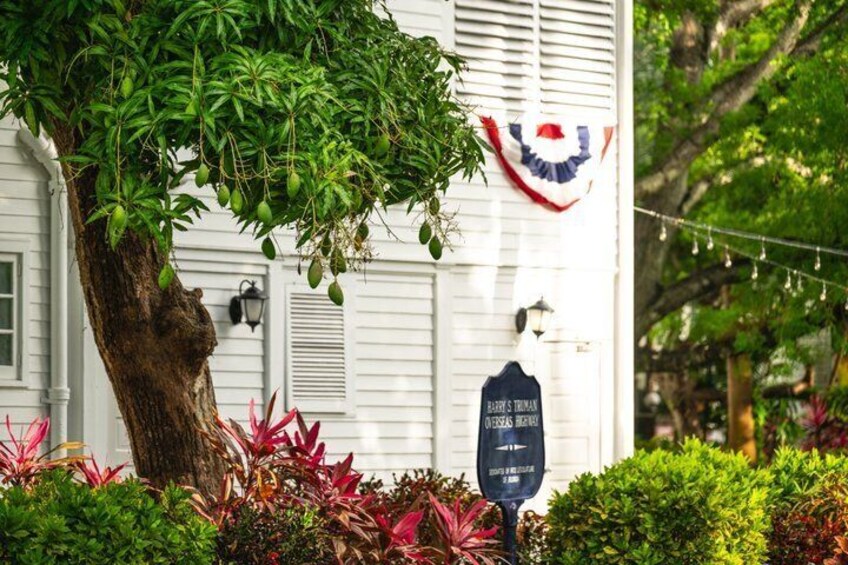 A white building with a flag, a tree, and a sign. 4