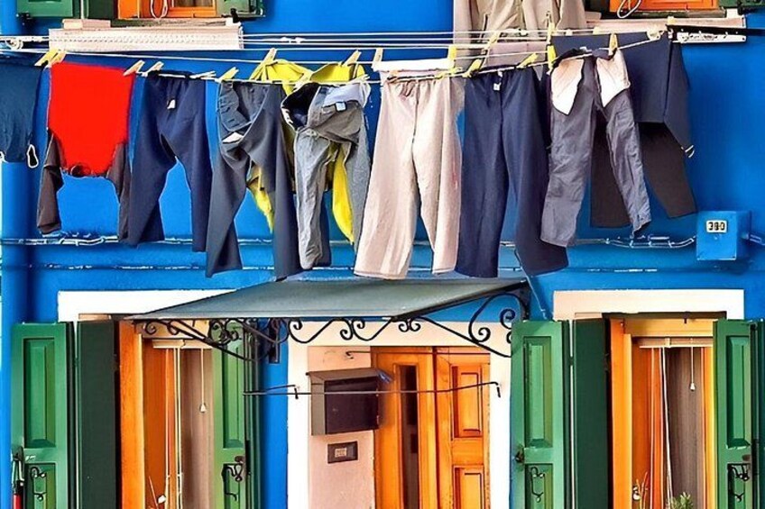 A colorful building with a clothesline hanging above a door, and a number '380' on the wall. 5