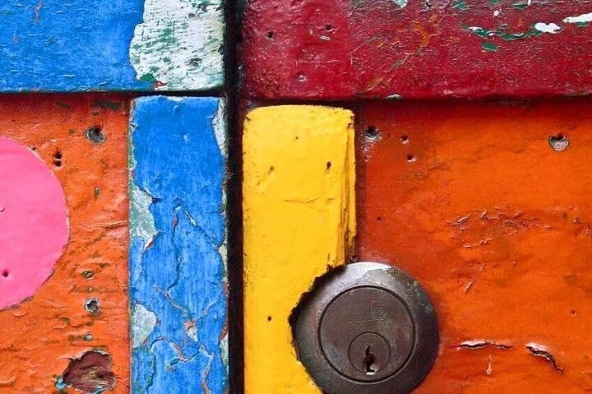 A colorful wall with peeling paint and a metal padlock. 3