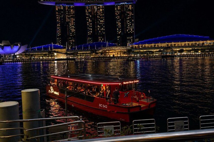 A red boat with passengers, a large illuminated building, and a body of water. 3