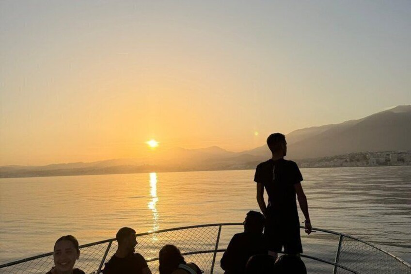 A sunset over a calm body of water with a person standing on a boat. 3