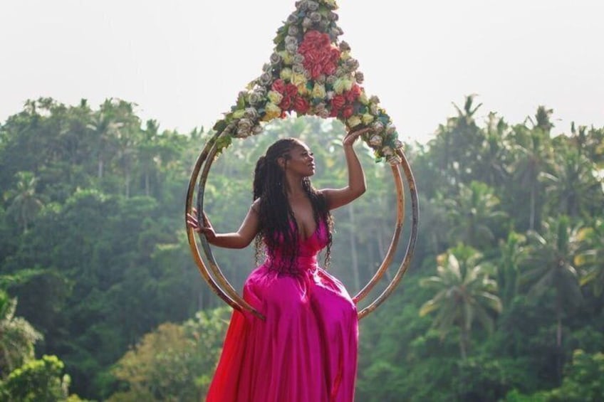 A person in a pink dress holding a floral arch. 5