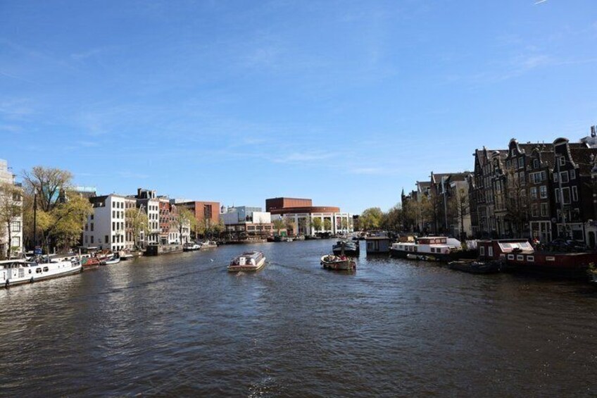 A river with boats, buildings, and a clear sky. 4