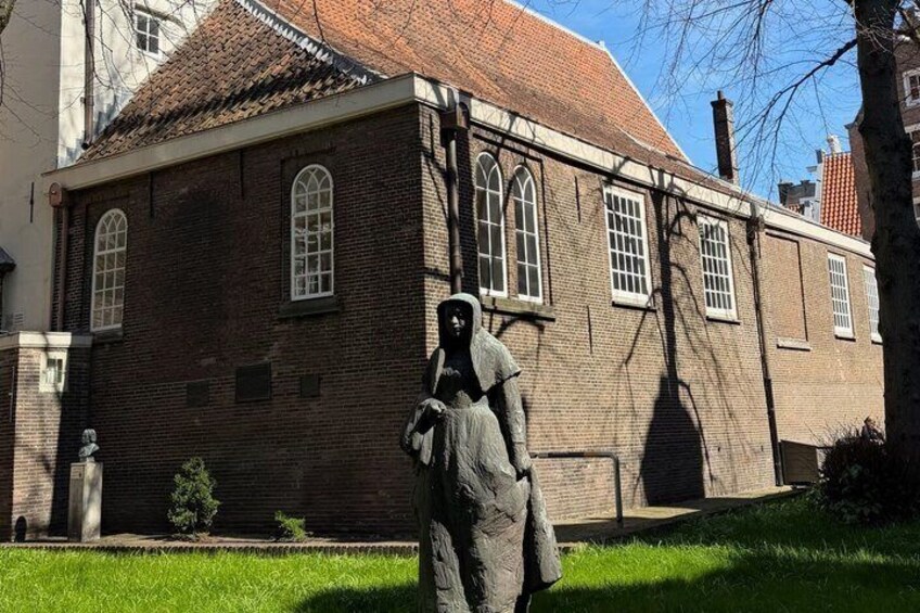 A brick building with arched windows and a statue in front. 3
