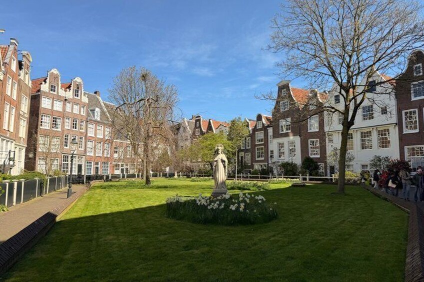 A park with a statue, well-maintained grass, and historic buildings. 2