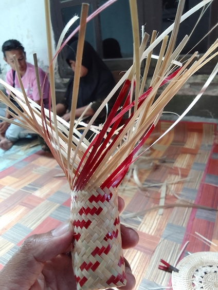 A hand holding a woven basket with red and beige patterns. 2